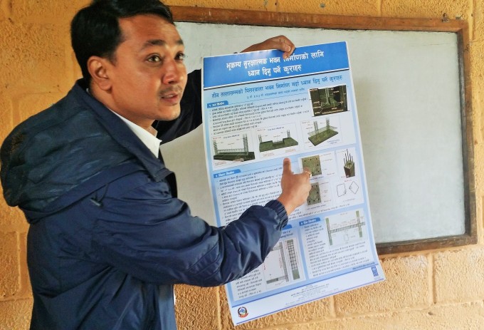 Er Ganesh Karmacharya shows phamplets related to earthquake safety