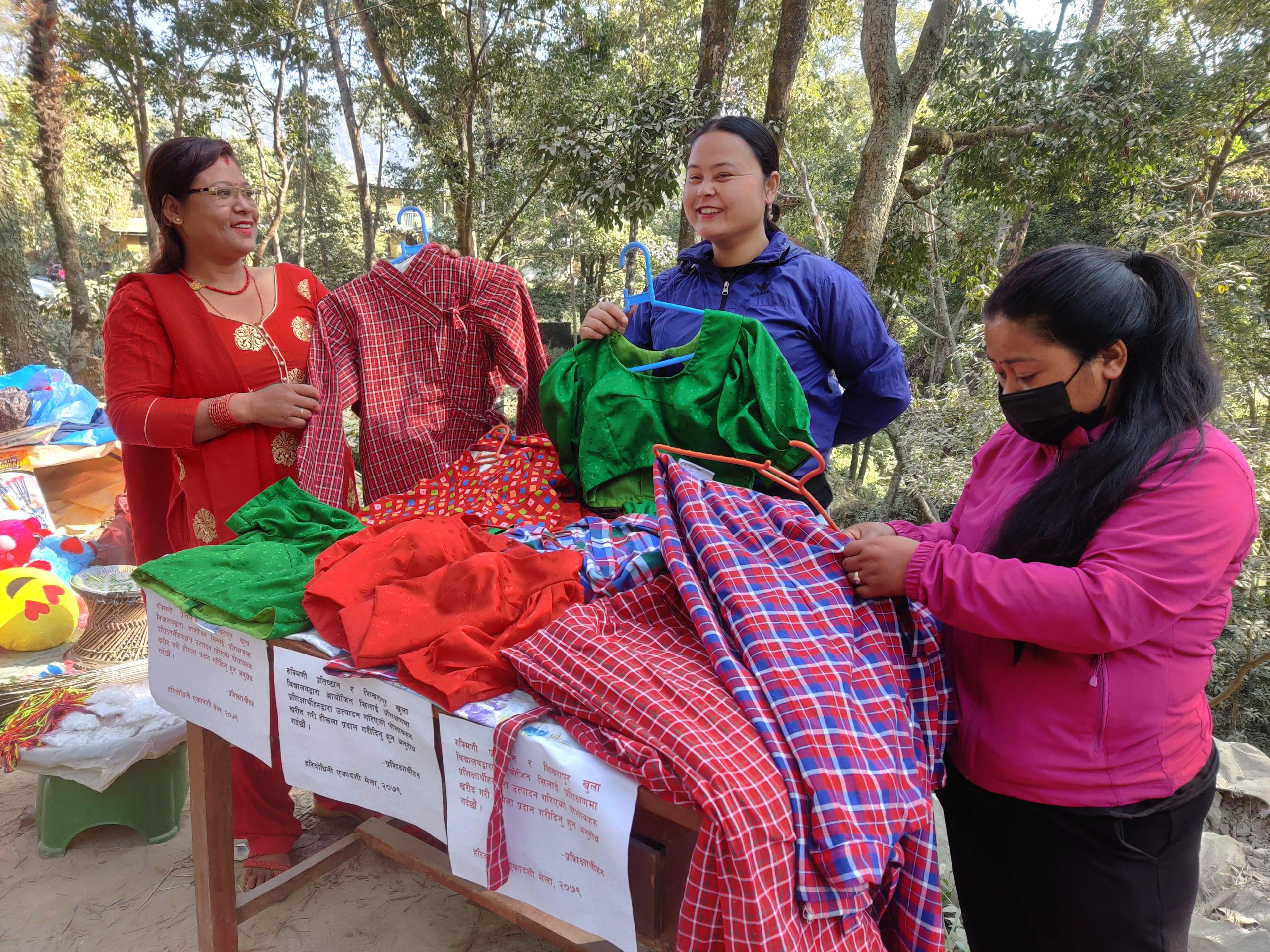 Women who take tailoring training from Rukmini Foundation showing the clothes to customer