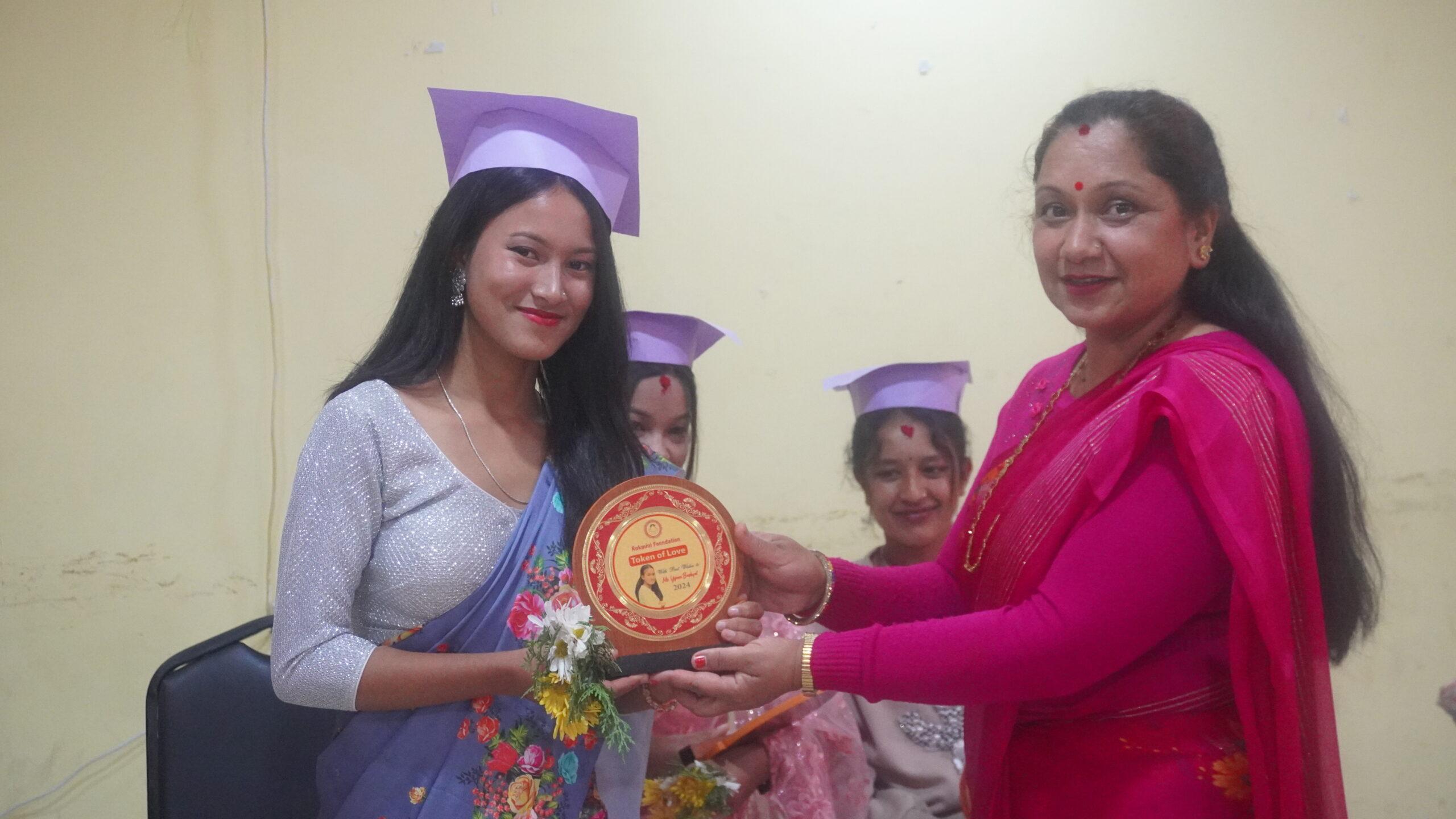 Celebrating Achievement! Rukmini Bahini Yojana receives her graduation plaque from guest didi Rajani during a proud moment at the Graduation Day ceremony_